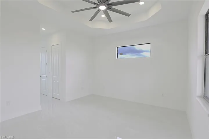 Empty room with baseboards, recessed lighting, a ceiling fan, and a raised ceiling