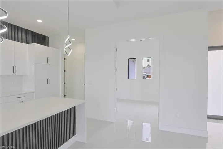 Kitchen with light countertops, hanging light fixtures, baseboards, white cabinets, and recessed lighting