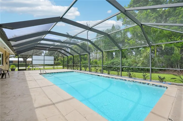 View of screened lanai with pool and view of backyard.