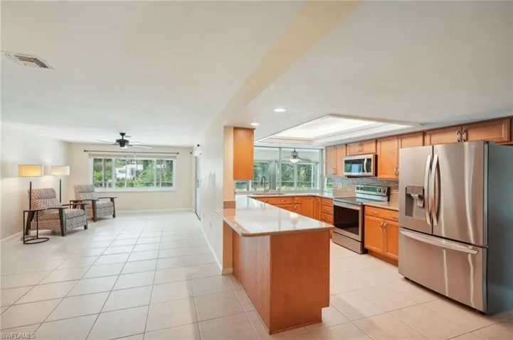 Family room and Kitchen featuring, sink, kitchen peninsula, stainless steel appliances, with sliding glass doors and windows to screened pool lanai