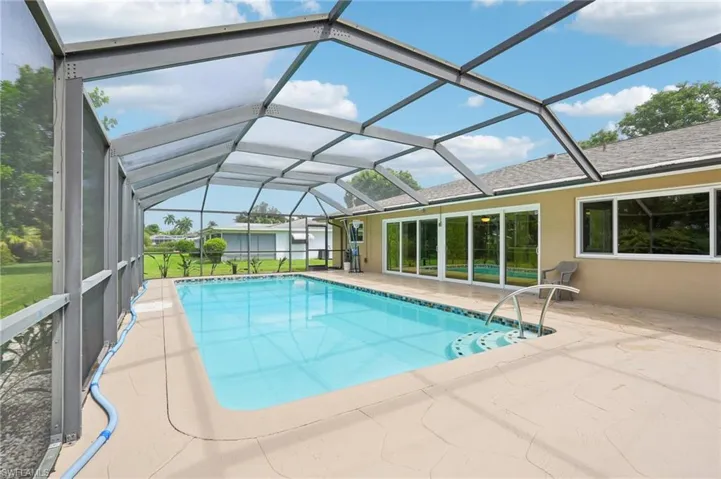 View of screened lanai with pool and view of sliders to sunroom.