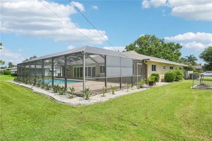 Rear view of house with a screened lanai, pool, patio area and far right is an area for your garden!