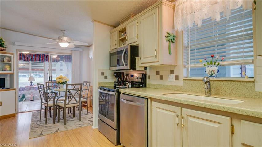 A kitchen with multiple views; including a kitchen window, well positioned over new(er) soft surface countertops and a matching backsplash. And; a view of the lake via the double door sliders.