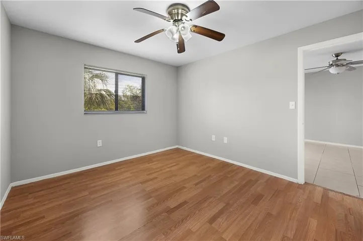 Room featuring wood-finish flooring, a ceiling fan with light fixture, and a window providing natural illumination