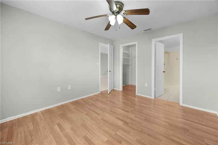 Spacious room featuring wood-finish flooring, light gray wall paint, and white trim