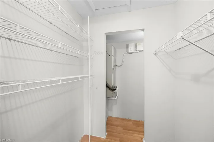Walk-in closet with white wire shelving, white painted walls, and wood-finish flooring