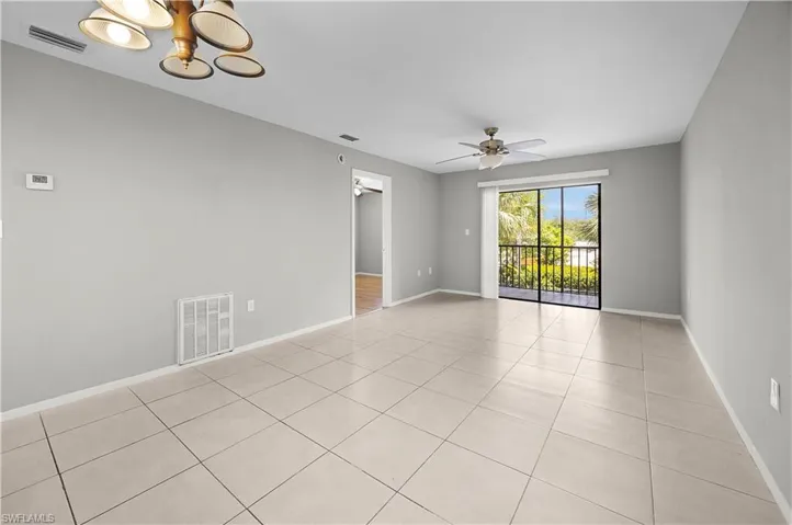 Expansive room featuring large format tile flooring, a ceiling fan with integrated lighting, and a sliding glass door leading to a balcony with black railings
