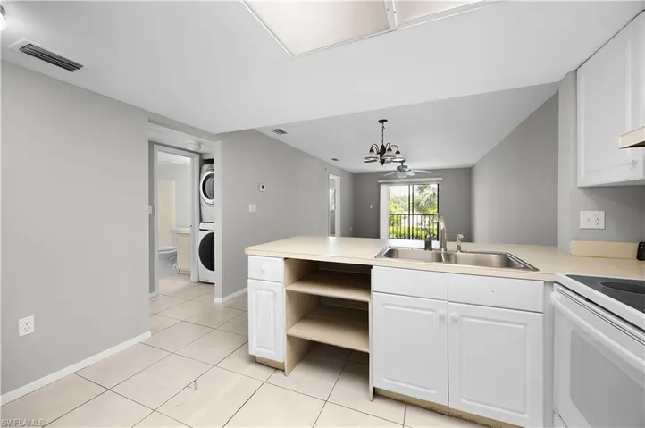 Kitchen featuring white cabinetry, light-toned countertops, and a double basin stainless steel sink