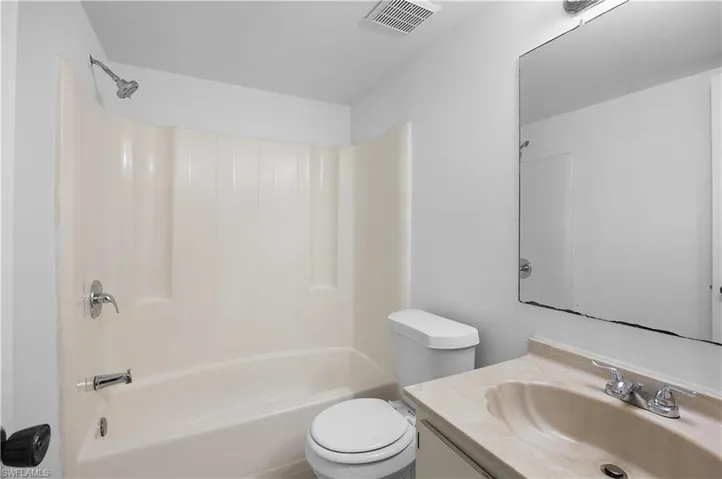 Bathroom featuring a tub/shower combination with chrome fixtures, a white toilet, and a vanity with an integrated sink