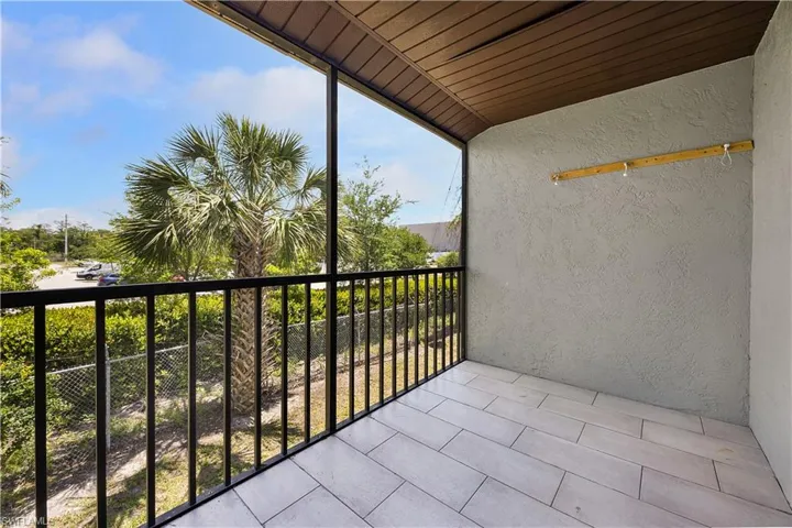 Screened balcony with plank-style tile flooring, a textured wall finish, and a wood-panel ceiling