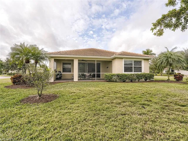 View of front of property with a front yard, a tile roof, and stucco siding