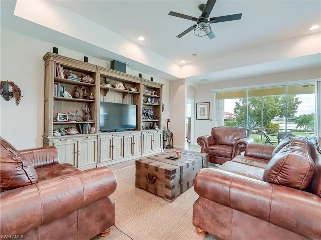 Living room with a ceiling fan, recessed lighting, arched walkways, and a tray ceiling