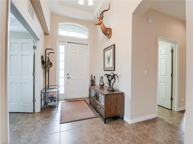 Entryway with light tile patterned flooring, arched walkways, and a tray ceiling