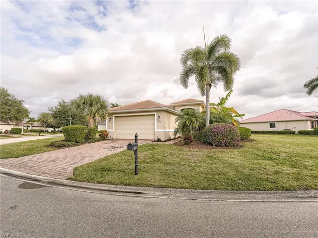 View of front facade featuring decorative driveway, a front yard, an attached garage, and stucco siding