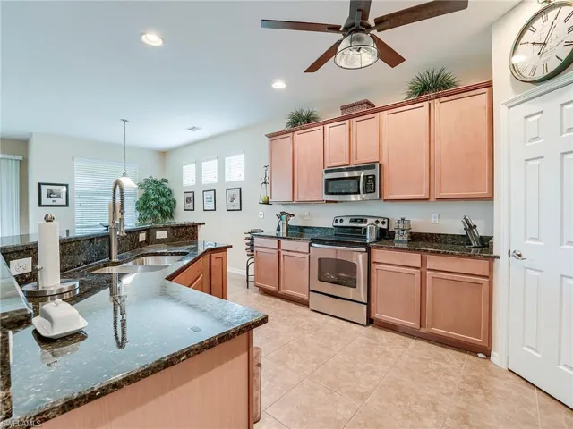 Kitchen with stainless steel appliances, pendant lighting, dark stone counters, recessed lighting, and ceiling fan