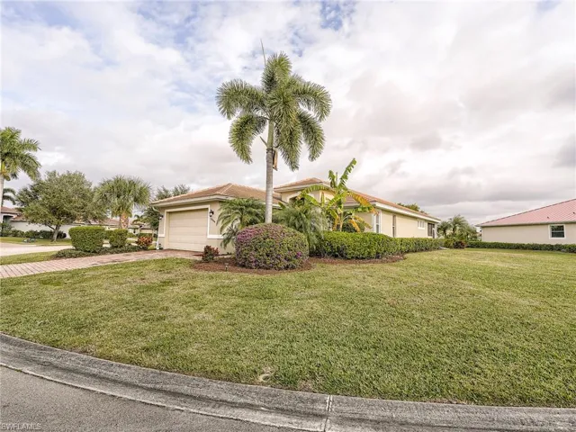 View of front facade featuring a front yard, concrete driveway, and an attached garage