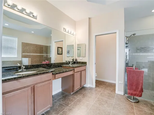 Full bath featuring a stall shower, double vanity, light tile patterned flooring, and recessed lighting