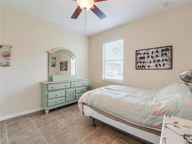 Tiled bedroom featuring a ceiling fan and baseboards