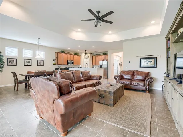 Living room with a ceiling fan, a raised ceiling, recessed lighting, and light tile patterned floors