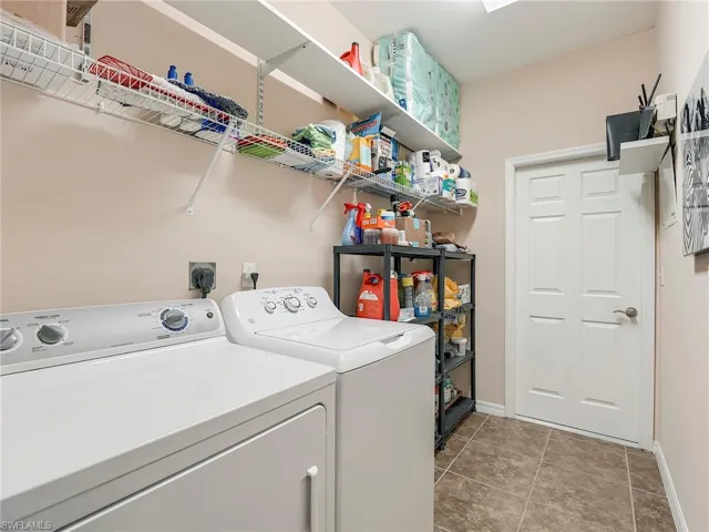 Laundry room featuring washing machine and clothes dryer and light tile patterned flooring