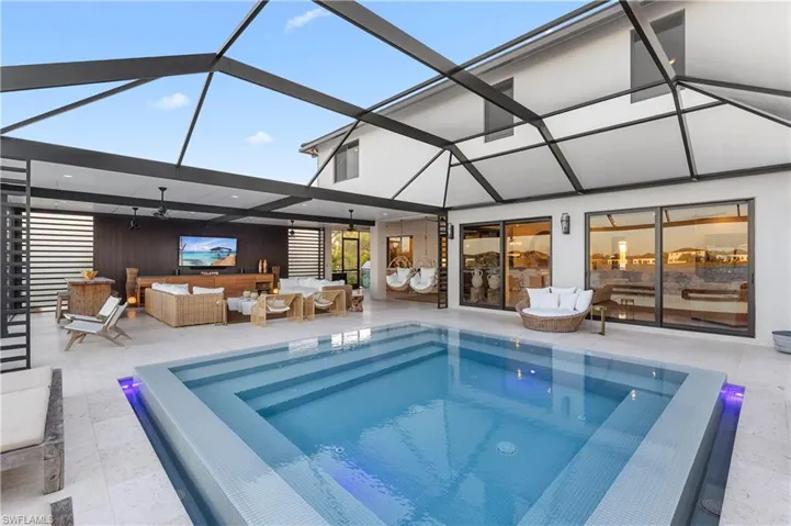 Back of property with a hot tub, outdoor furniture, a patio area, and a lanai