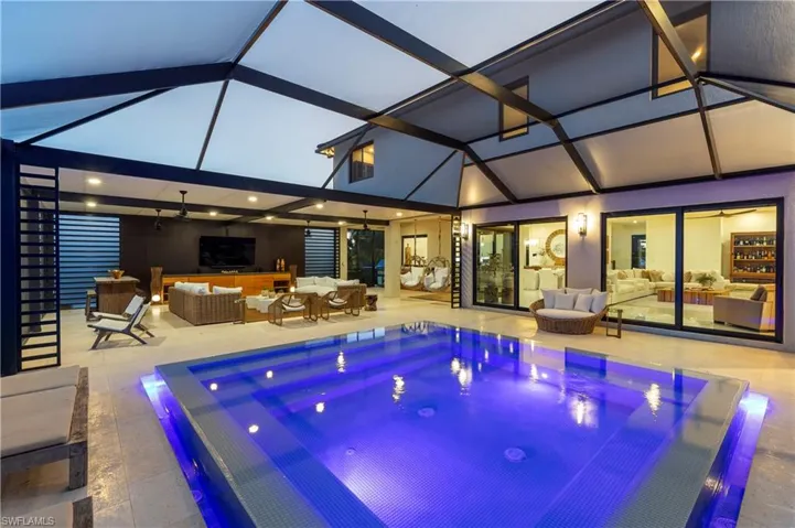 View of swimming pool with an infinity pool, an outdoor lounge area, a hot tub, and glass enclosure