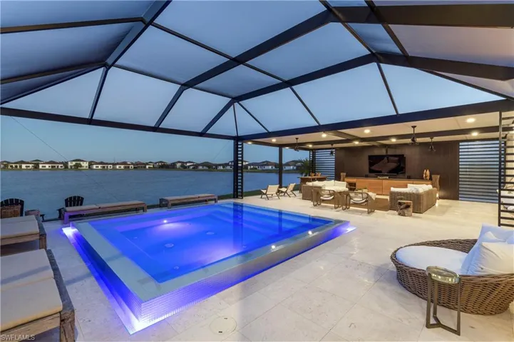 Outdoor pool featuring an in-ground hot tub, an outdoor lounge area, glass enclosure, and a patio