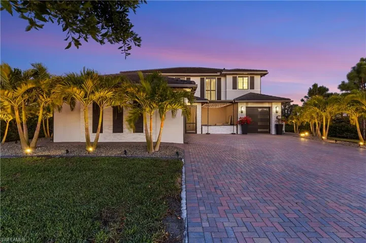 View of front of home with stucco siding, decorative driveway, a lawn, and an attached garage