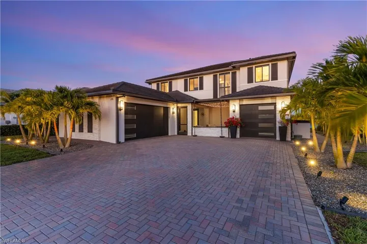 View of front of property with decorative driveway, a garage, and stucco siding