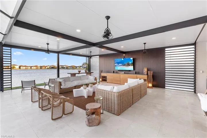 Living area with expansive windows, a residential view, wooden walls, and beam ceiling