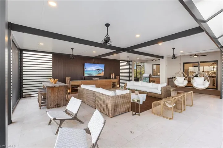 Living room with wood walls, recessed lighting, beam ceiling, and a ceiling fan