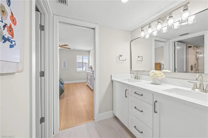 Bathroom with double vanity, light wood-type flooring, connected bathroom, and a shower