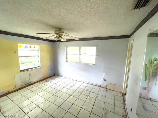 Tiled spare room with ceiling fan and a textured ceiling