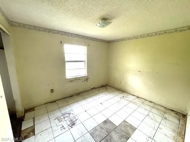 Tiled spare room featuring a textured ceiling