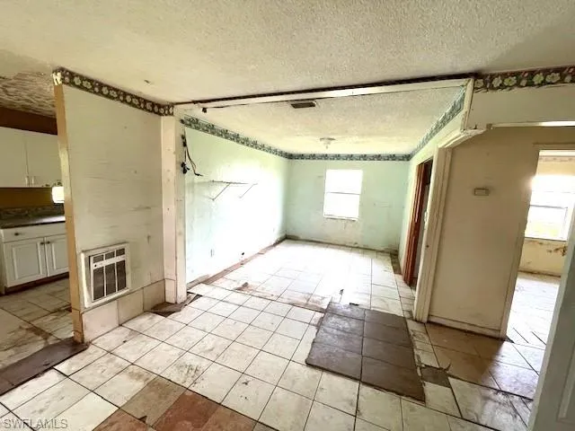 Spare room with a healthy amount of sunlight, light tile flooring, and a textured ceiling