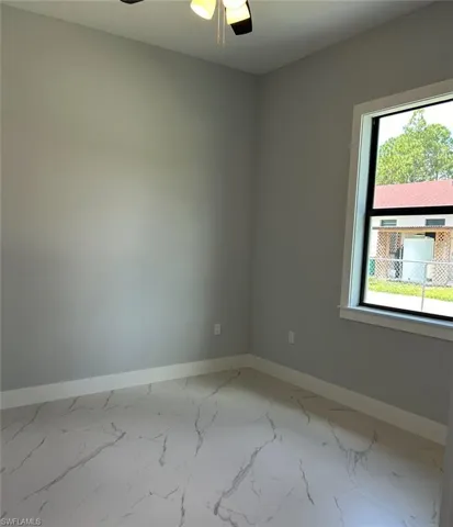 Unfurnished room featuring ceiling fan and a wealth of natural light