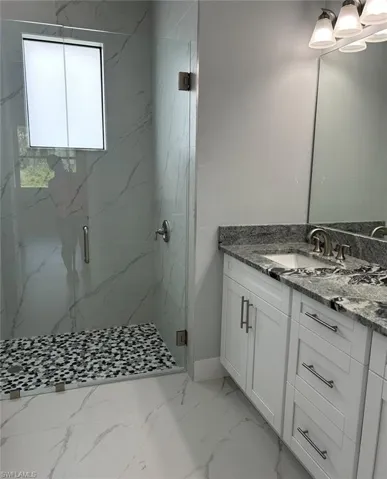 Bathroom featuring tile patterned floors, vanity, and walk in shower