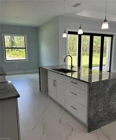 Kitchen featuring sink, dark stone counters, and light tile patterned floors