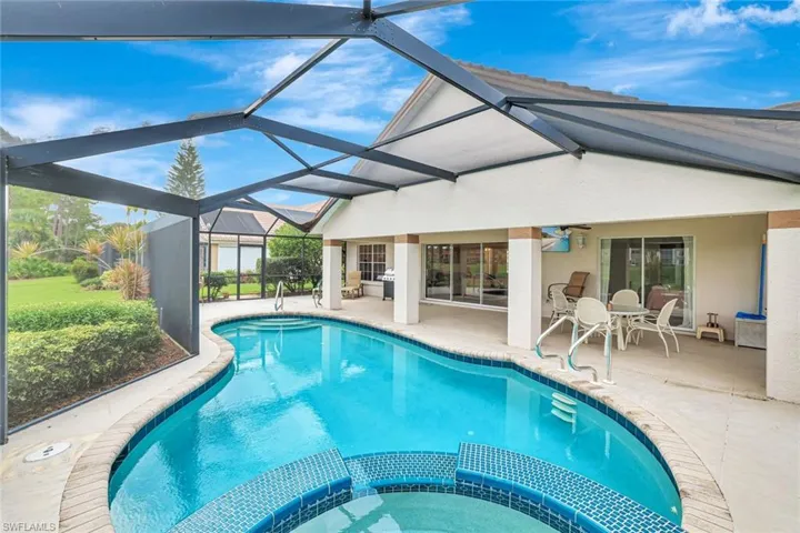 View of pool with a pool with connected hot tub, a patio area, outdoor dining space, and a lanai
