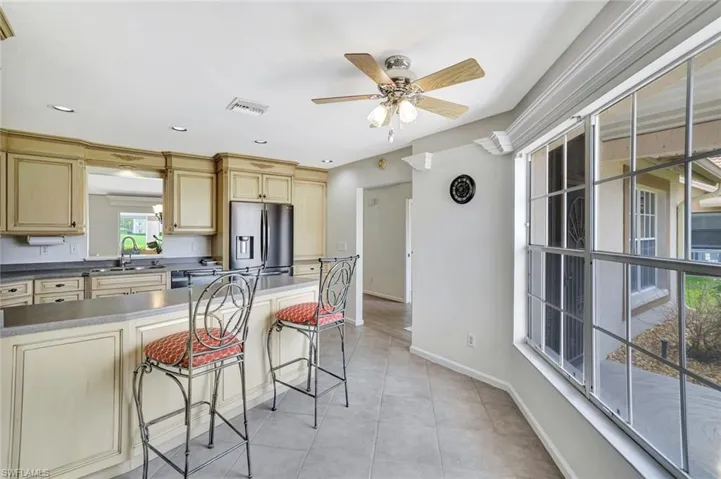 Kitchen with stainless steel fridge, a sink, a breakfast bar, ceiling fan, and light tile patterned floors