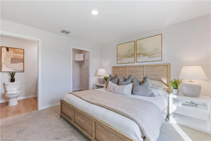 MODEL HOME - Bedroom featuring a walk in closet and light carpet
