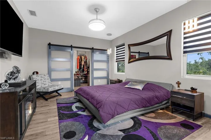 Bedroom with a barn door, a spacious closet, and light wood-type flooring