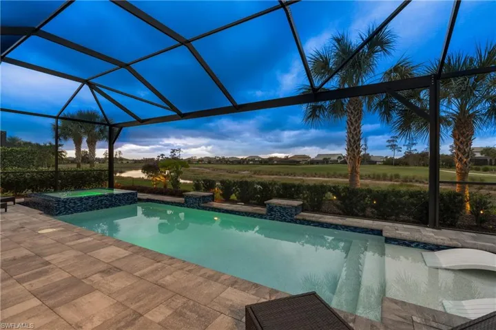 View of pool featuring a lanai, a pool with connected hot tub, and a residential view