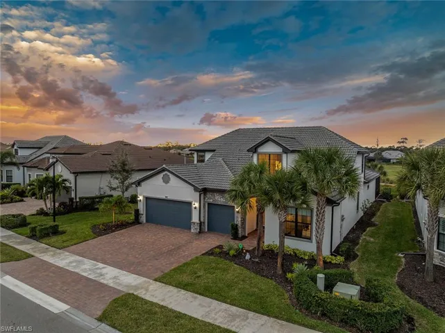 View of front of house featuring stucco siding, decorative driveway, a yard, and a tiled roof