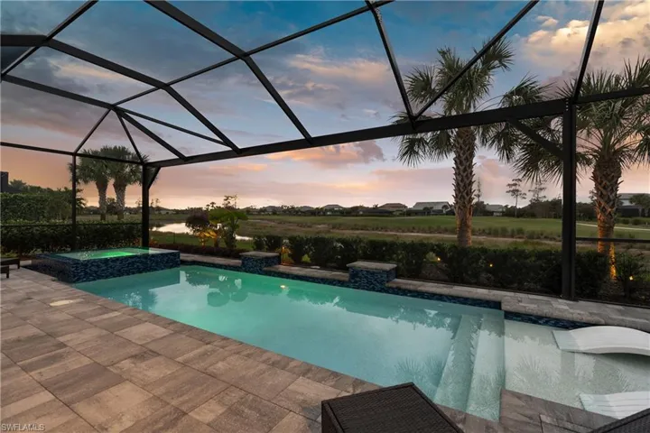 View of pool with screen enclosure, and a pool with connected hot tub