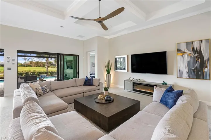 Living room featuring coffered ceiling, beamed ceiling, a ceiling fan, and ornamental molding
