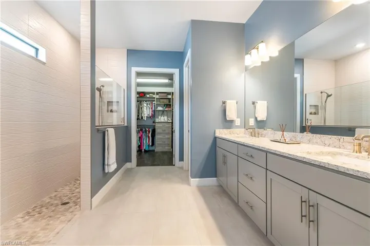 Bathroom with walk in shower, a spacious closet, double vanity, and light tile patterned flooring