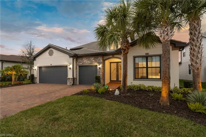 Ranch-style house featuring stucco siding, an attached garage, decorative driveway, a yard, and stone siding