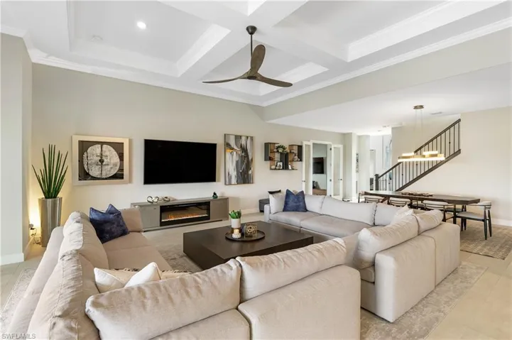 Living room featuring light tile patterned floors, coffered ceiling, a ceiling fan, and a beam ceiling,