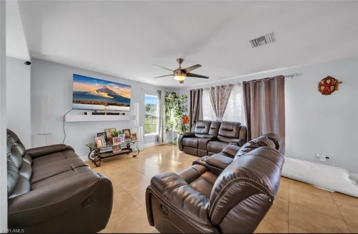 Living area with tile patterned floors and a ceiling fan